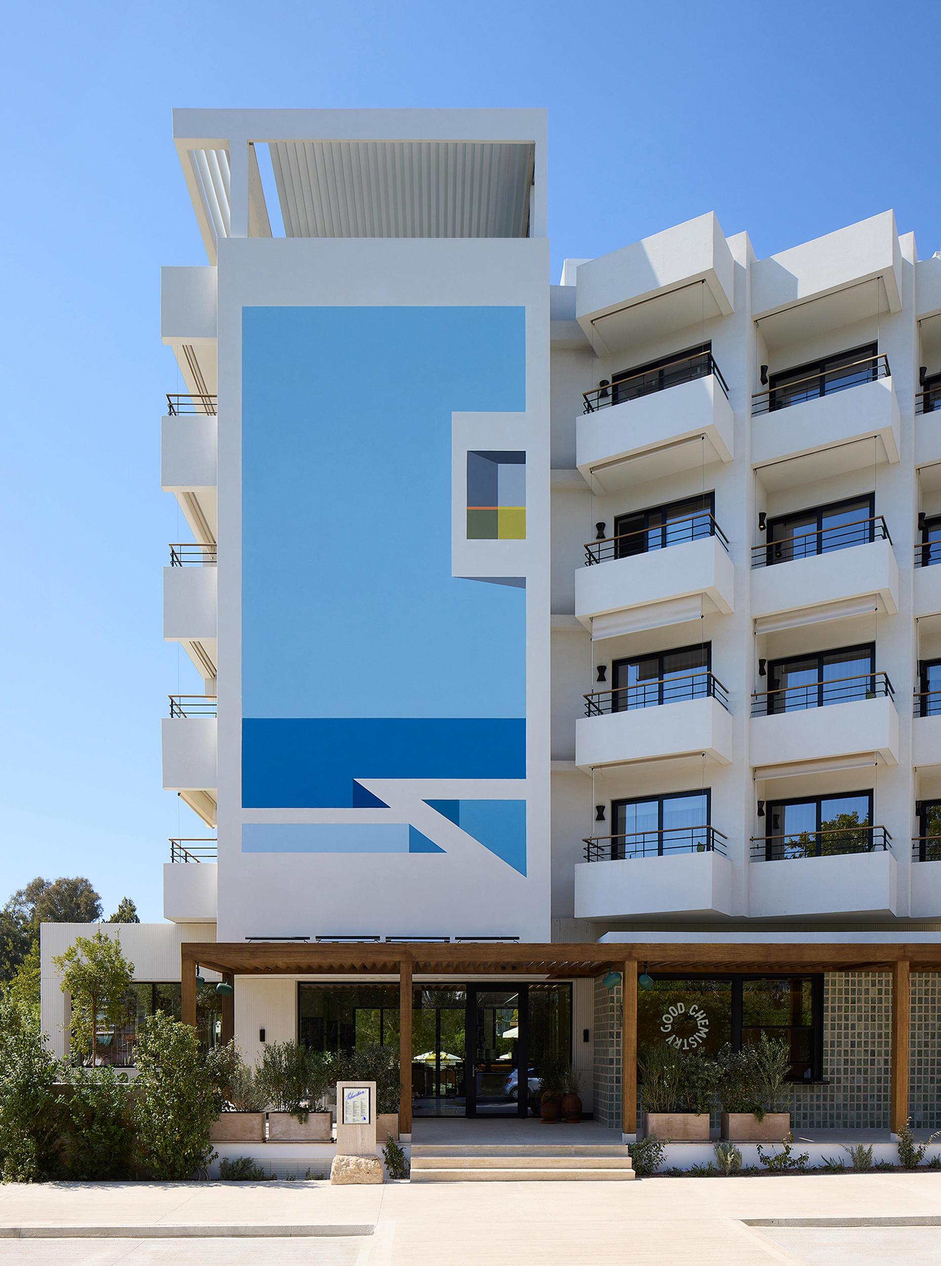 Exterior view of Ace Hotel & Swim Club Athens, featuring a modern architectural design with clean lines and a warm, inviting facade. Surrounded by greenery, the building exudes a welcoming atmosphere