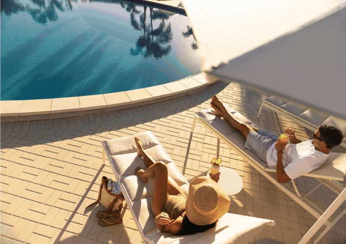 A gif of images including a couple relaxing poolside, a couple dining at RARE  1981, a couple walking along a scenic bridge, and a family lounging in a spacious suite