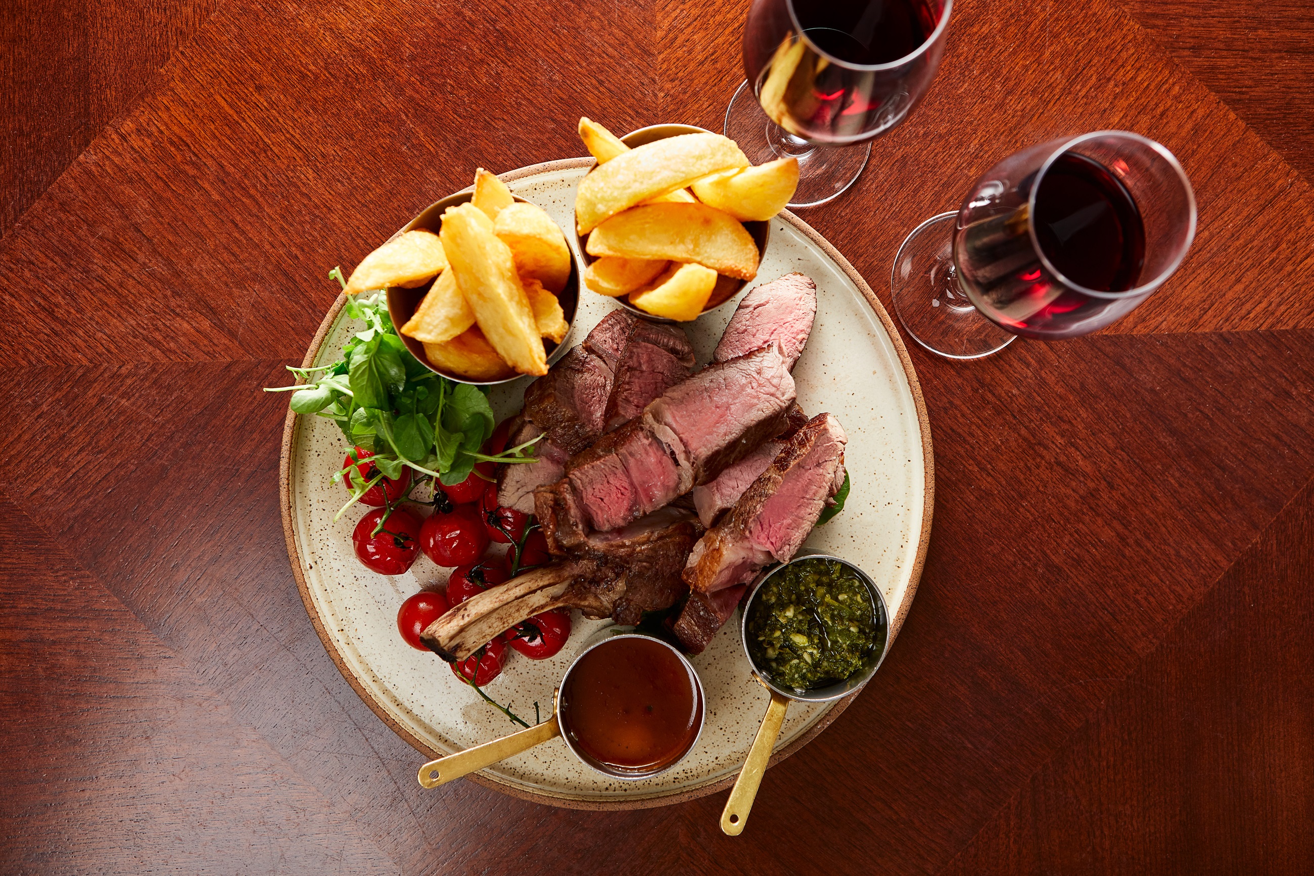 Chopped rib of beef with sides and glasses of red wine